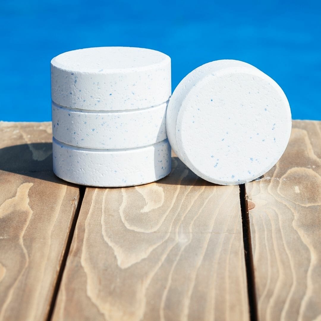 Chlorine tablets for a pool stacked on pool deck.