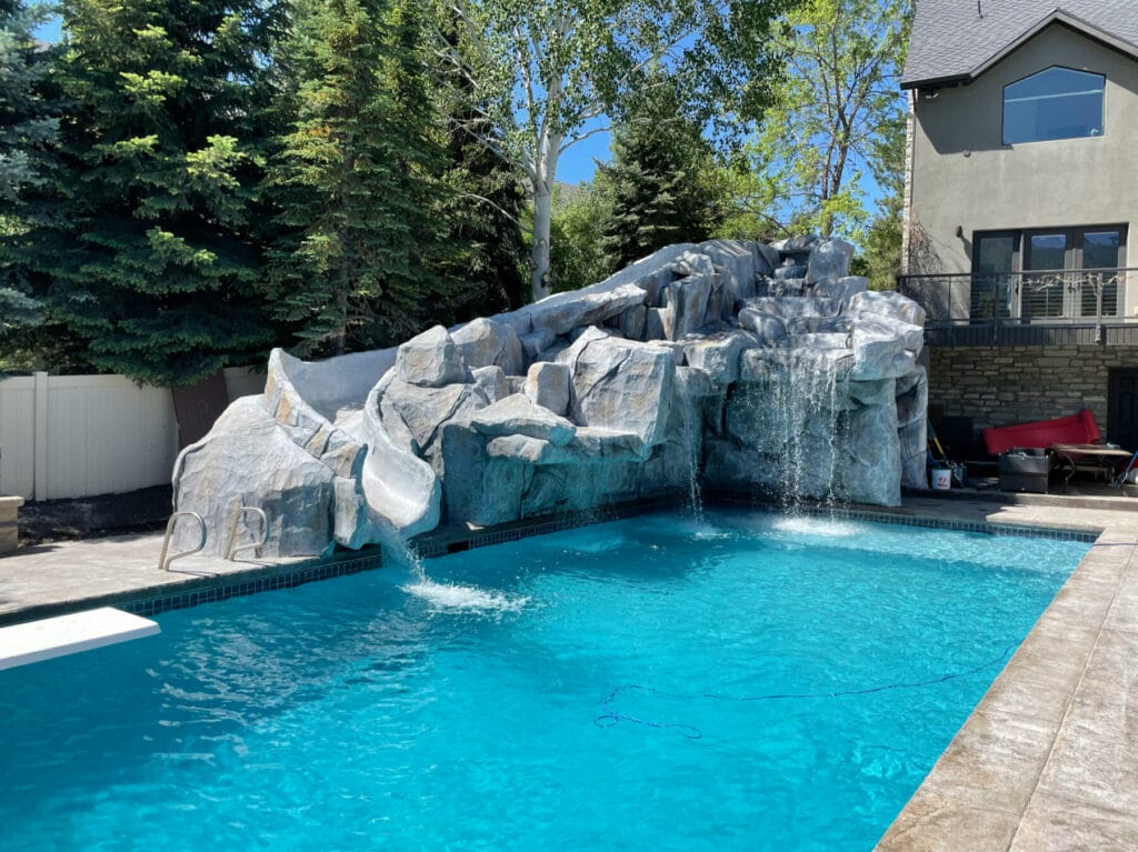 Swimming pool with custom rock waterfall pool slide in Salt Lake City, Utah - Stevenson Brothers Custom Pools