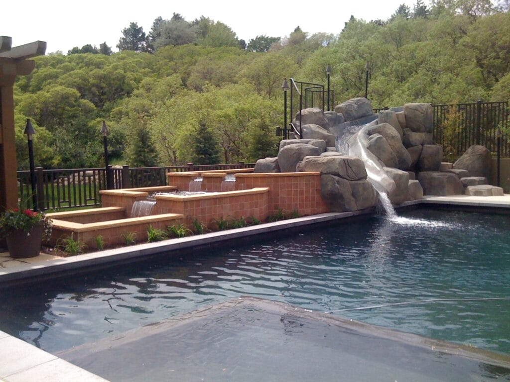 Custom pool with natural rock slide design and infinity pool hot tub and waterfalls in Salt Lake City, Utah - Stevenson Brothers Custom Pools