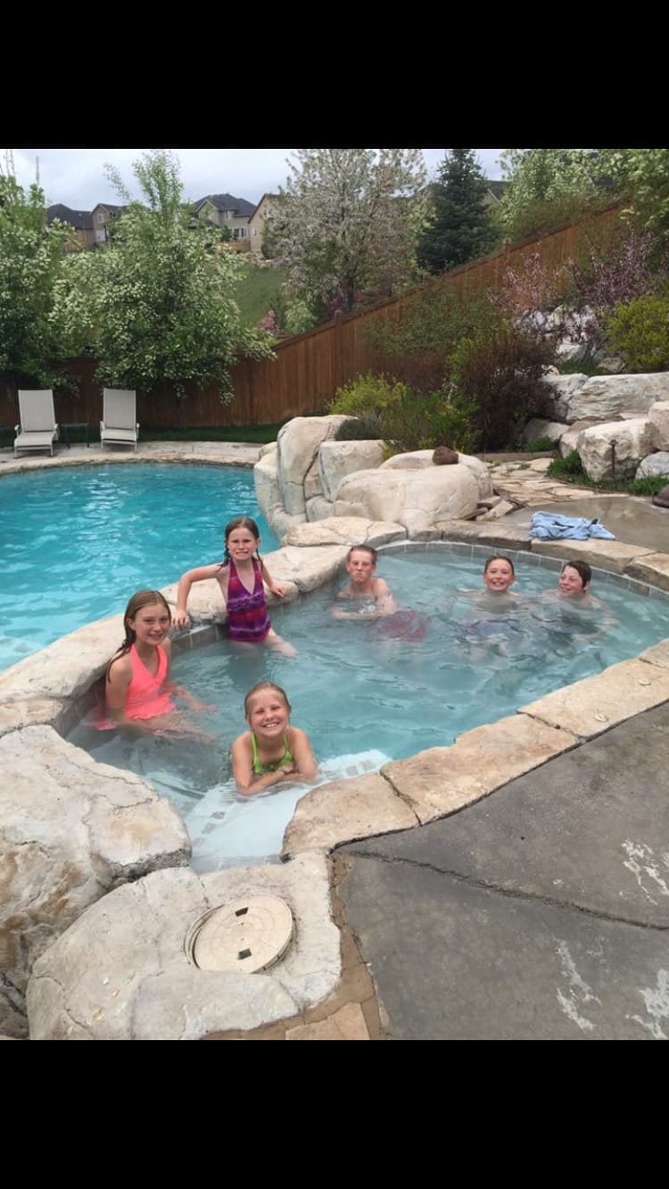 Utah family enjoys custom swimming pool & hot tub spa with natural rock work design