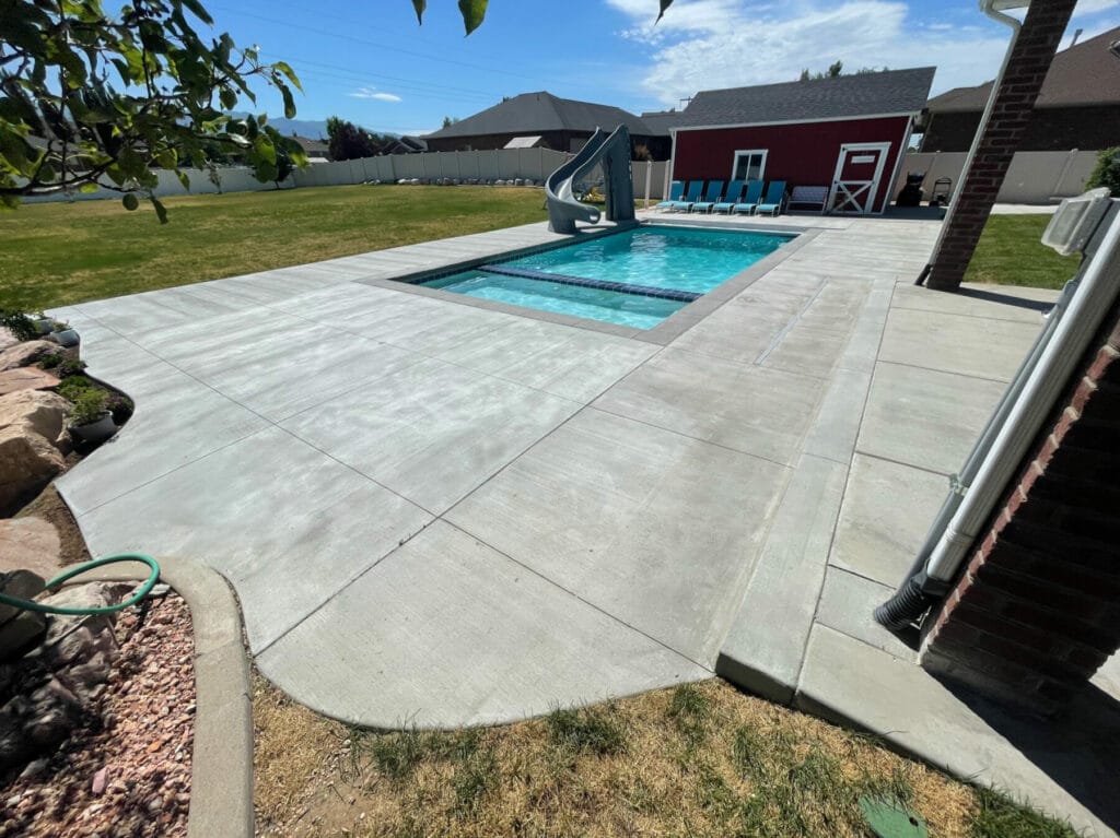 Custom concrete swimming pool with slide and hot tub in Salt Lake City, Utah -backyard patio concrete contractor project