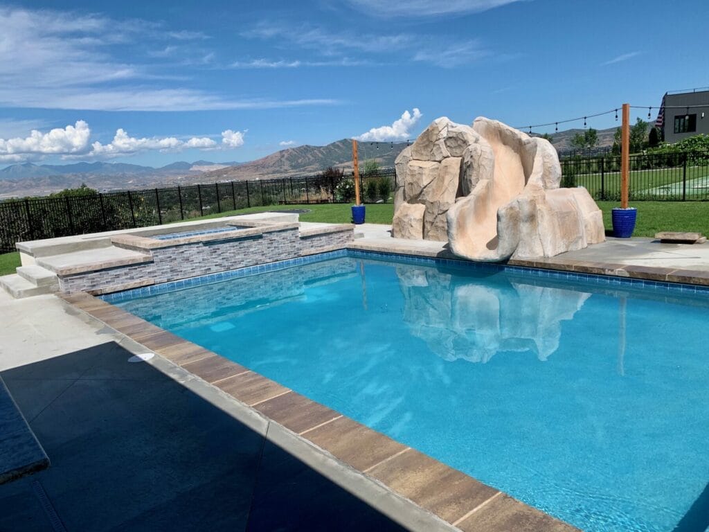 Custom swimming pool with artificial concrete rock pool slide and hot tub in Salt Lake City, Utah built by Stevenson Brothers Custom Pools - SBI Waterfalls
