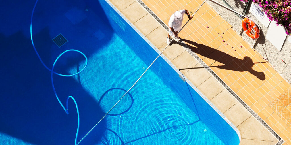 Professional contractor cleans salt water swimming pool, tests water chlorine levels & balances pH